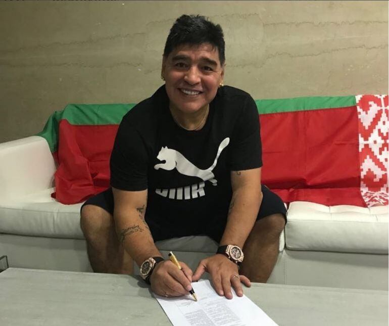 Diego Armando Maradona posa con el contrato del Dinamo Brest. 