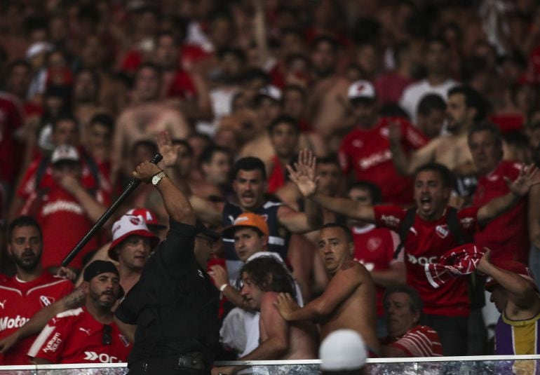 Un policía brasileño se enfrenta a aficionados de Independiente, en la final de la Copa Sudamericana, en Maracaná