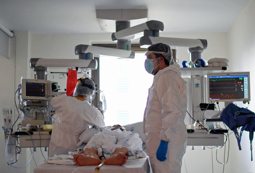 Personal sanitario atendiendo a un paciente de COVID-19 en la UCI.