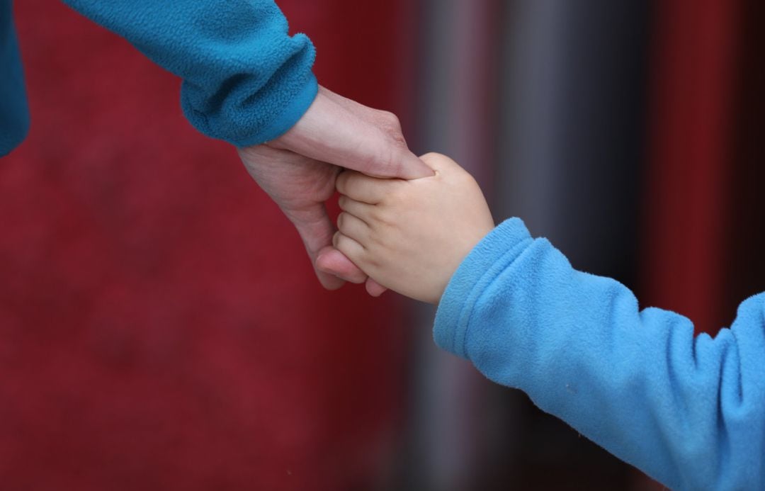 Un niño camina de la mano.