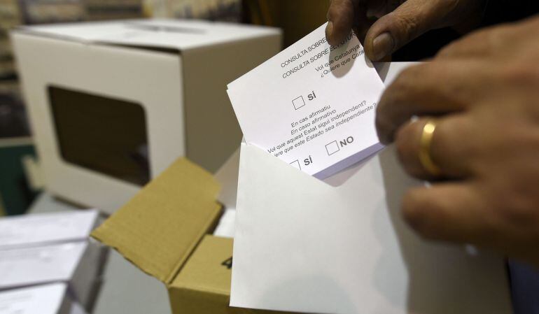 A volunteer places a blank ballot paper into an envelope at a school in Barcelona on November 9, 2014 Catalonia votes on November 9, 2014 in a symbolic vote on independence from Spain. Spain's Constitutional Court on November 4 ordered the Catalan government to suspend the planned vote but regional leader Artur Mas has vowed to press ahead with Sunday's ballot, which will be organised by volunteers without an official electoral roll. AFP PHOTO/LLUIS GENE.