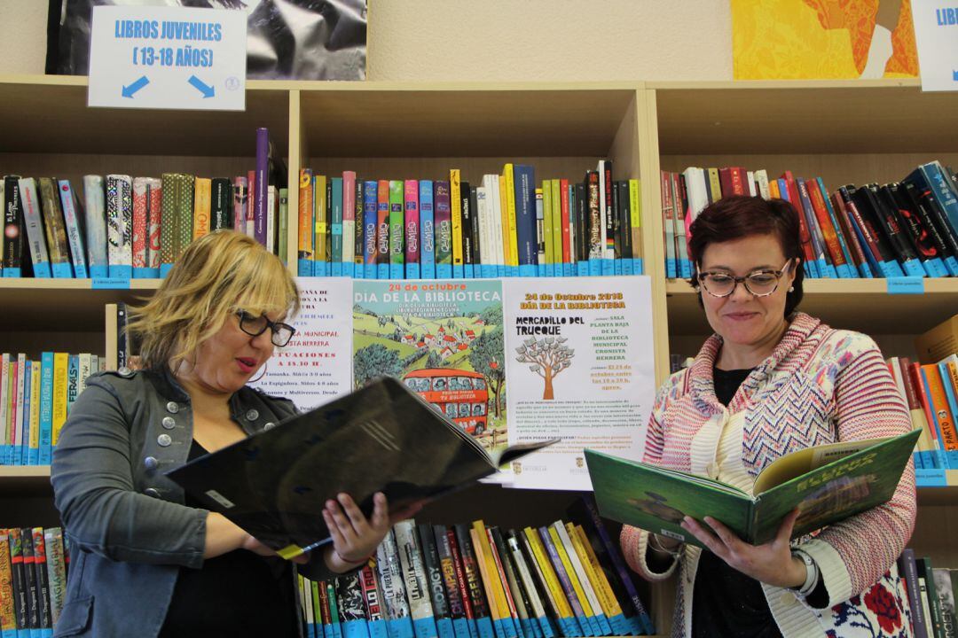 La concejal de Educación Sonia Martín y la bibliotecaria Nuria Tardáguila observan varios libros en la biblioteca Cronista Herrera de Cuéllar. 