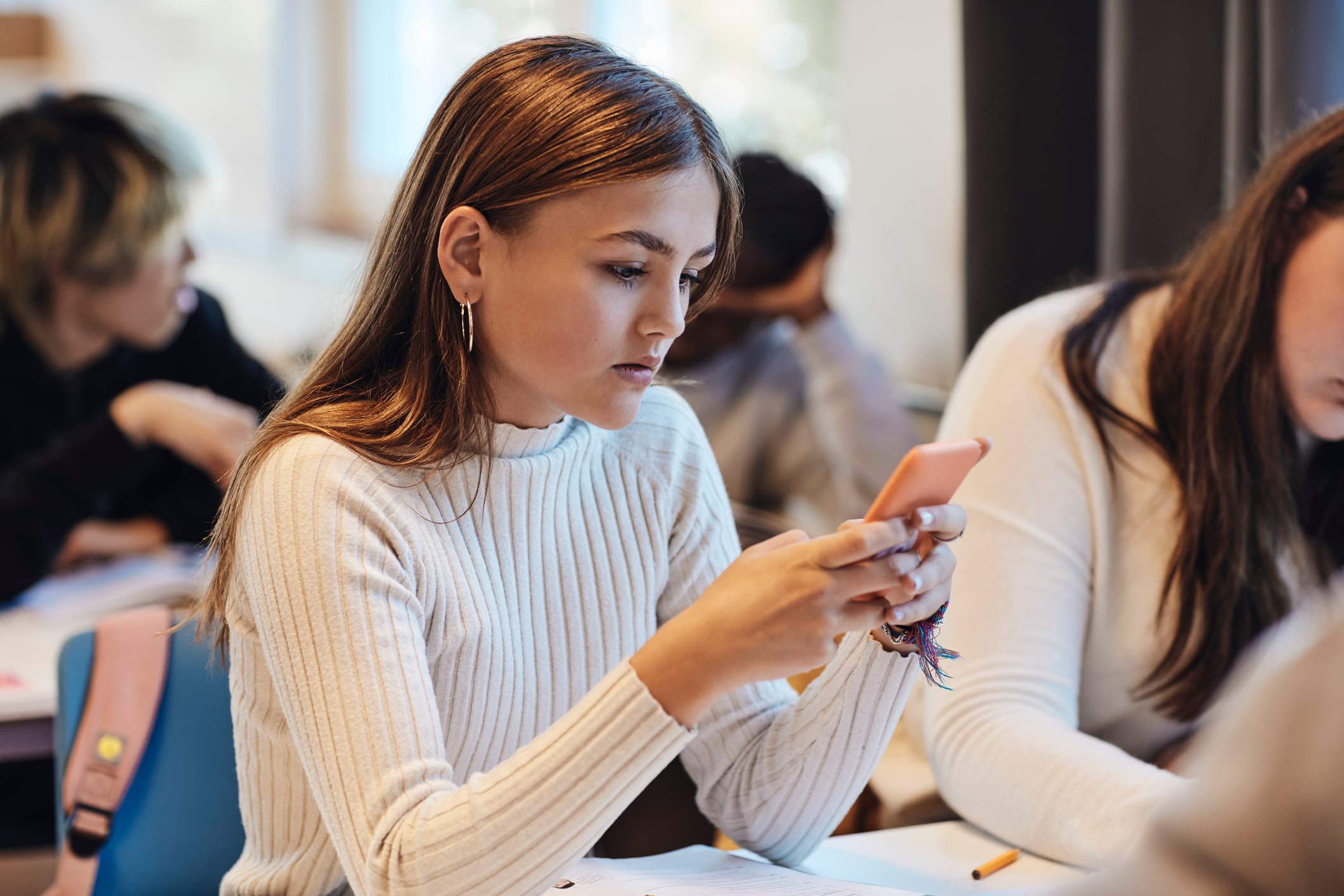 Una adolescente consulta su teléfono móvil en clase.