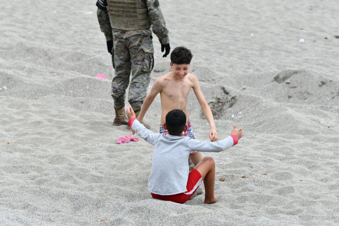 Dos niños se saludan el mismo día de una jornada marcada por las devoluciones en caliente que están efectuando a los migrantes que han entrado en Ceuta procedente de Marruecos, a 18 de mayo de 2021, en Ceuta, (España). Al menos 2.700 personas han sido devueltas a Marruecos en las últimas horas tras asaltar la frontera de Ceuta con la complicidad de las autoridades marroquíes. El ministro del Interior ha defendido la españolidad de Ceuta, una ciudad tan española como Sevilla o Madrid y se ha comprometido a defender la integridad de la frontera con la devolución inmediata de los que entren. 
 