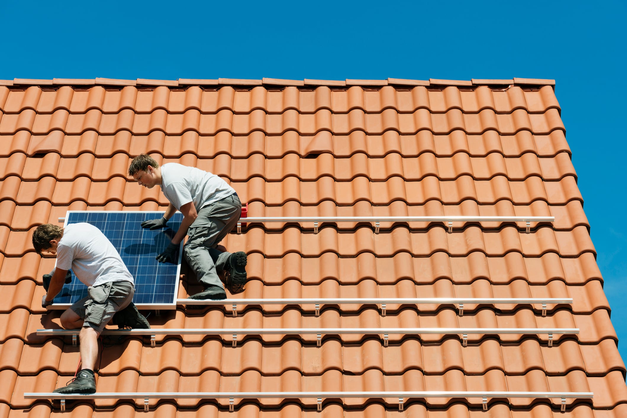 Operarios instalan unas placas solares en el tejado de una vivienda