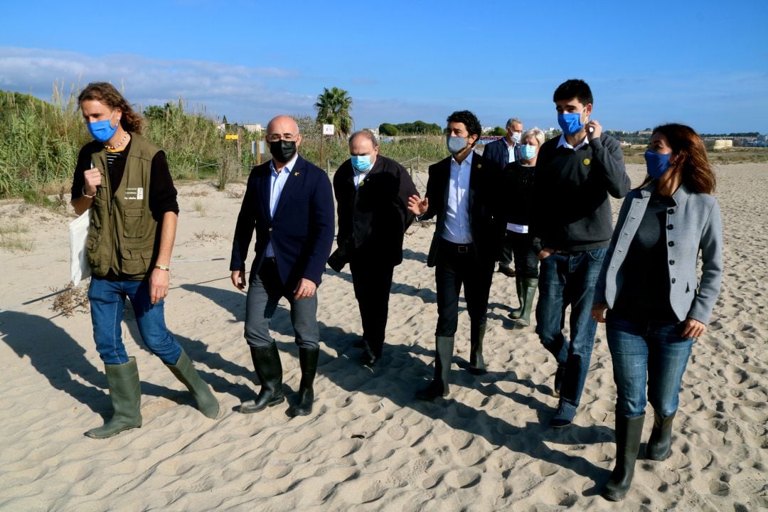 Pla general del conseller Calvet, altres representants del Govern i dels ajuntaments de Tarragona i Altafulla caminant per la platja, a tocar de la desembocadura del riu Gaià. 