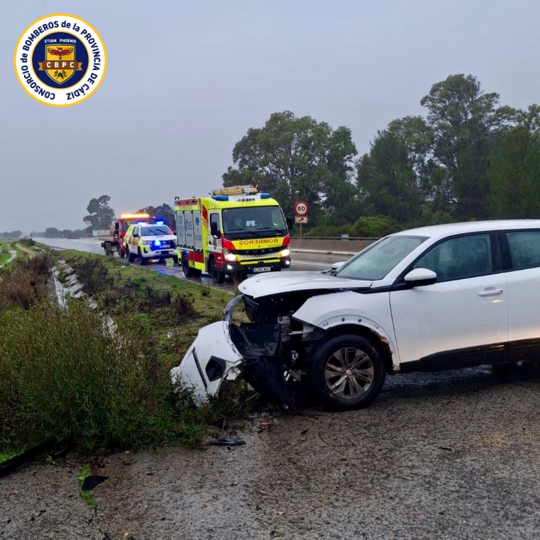 Los bomberos durante su intervención tras la salida de la vía de un vehículo en la A-2006, en La Barca de la Florida