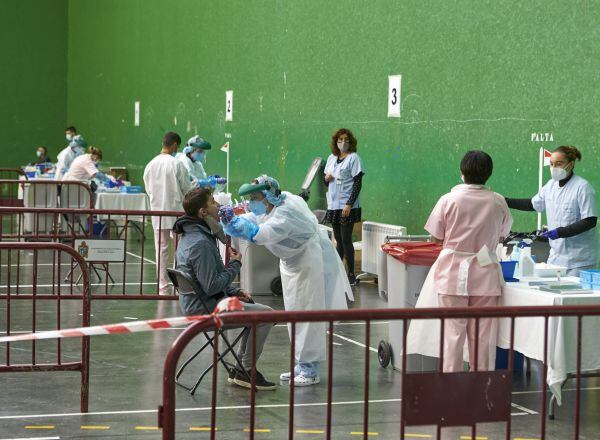 Una mujer es atendida mientras tres trabajadoras hablan en el dispositivo de extracción de pruebas PCR instalado en el Frontón Arizmendi de Ermua, Vizcaya, Euskadi (España), a 26 de octubre de 2020. El Departamento de Salud y Osakidetza, en el marco de los trabajos de vigilancia y control de la pandemia del covid-19 que realizan, han solicitado a los vecinos de Ermua y Mallabia, entre 13 y 40 años de edad, que acudan a realizarse una prueba PCR a partir de hoy al Frontón Arizmendi y hasta el jueves (si fuera preciso), 29 de octubre.  26 OCTUBRE 2020;CORONAVIRUS;SALUD;PANDEMIA;ERMUA;PCR;CRIBADO;PRUEBAS;INFECCIONES;CONTAGIOS  Ion Alcoba / Europa Press  26/10/2020