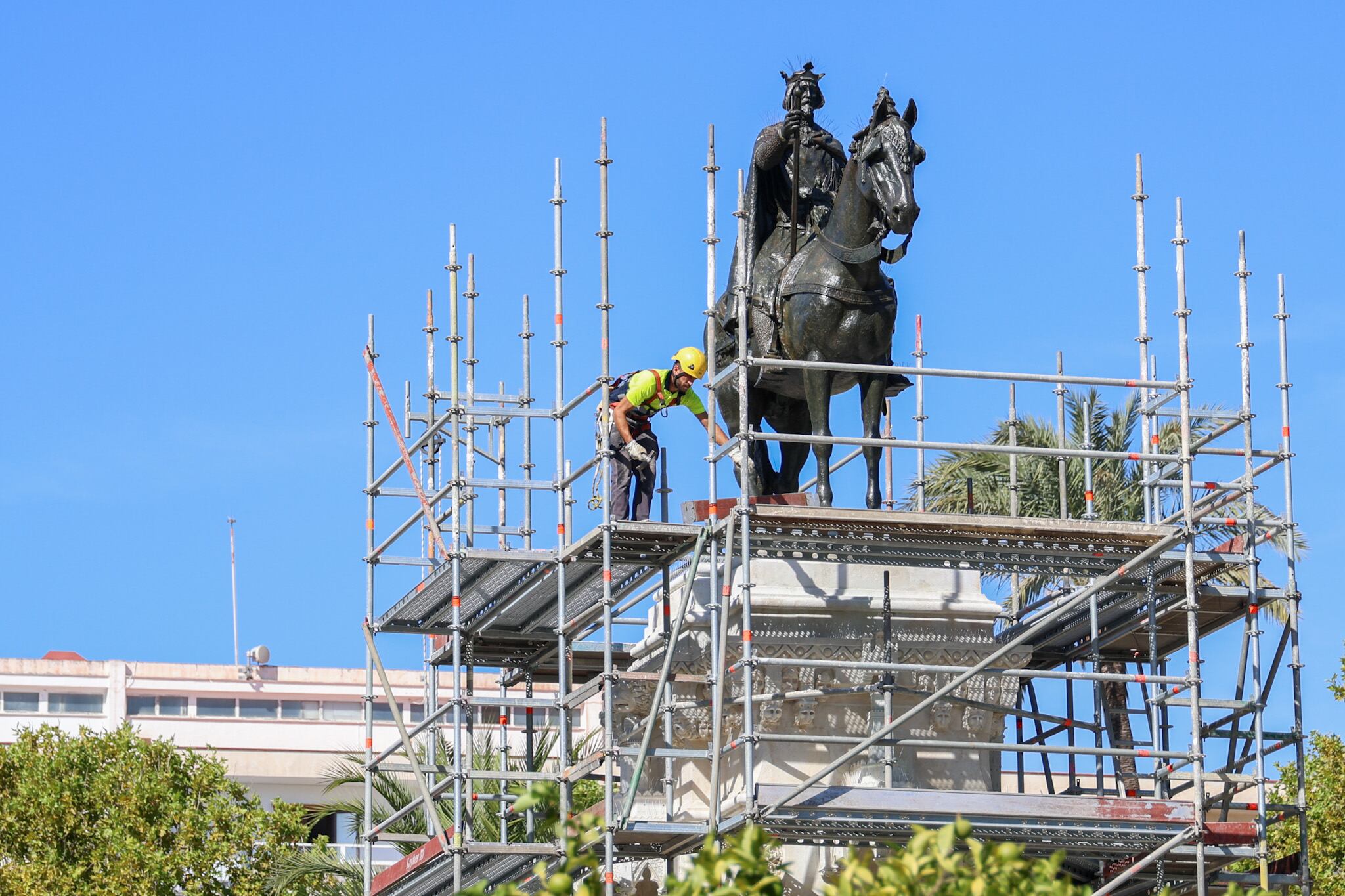 Un operario retira los andamios que han rodeado el monumento al Rey San Fernando en los últimos meses