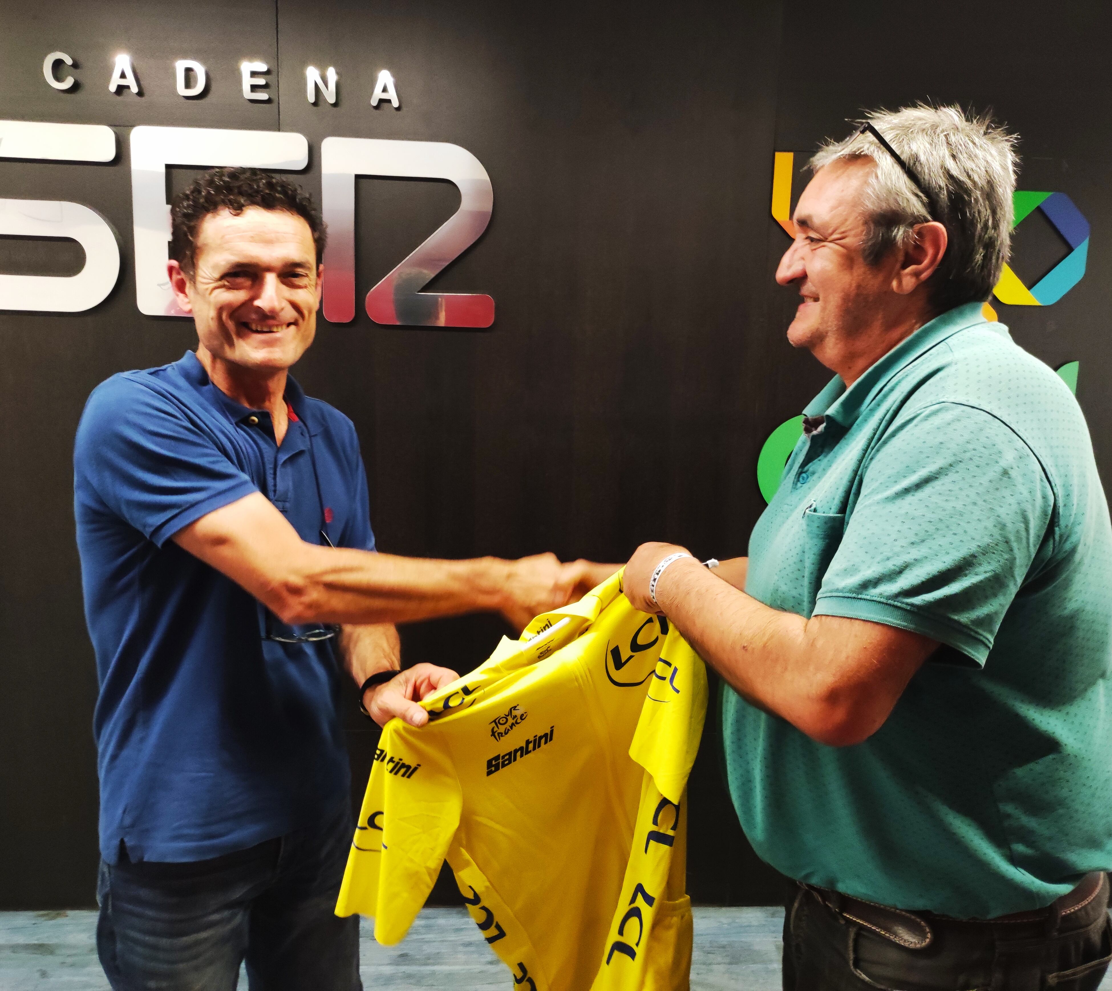 El jefe de deportes de SER Vitoria Javier Lekuona (dcha) entrega a iñaki Uriarte (izda) el maillot oficial del Tour de Francia 2023 firmado por Jonas Vingegaard