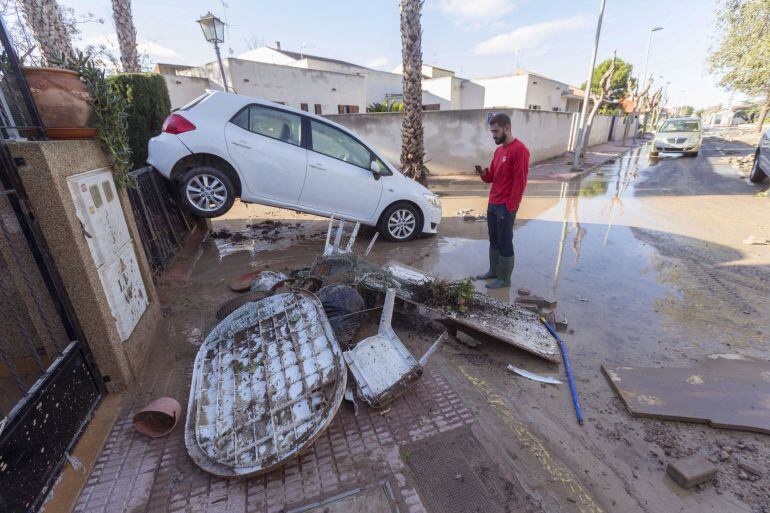 Un vecino del municipio murciano de Los Alcázares, junto a un coche que quedó encajado en la puerta de una vivienda, tras las inundaciones causadas por las intesas lluvias caídas en los municipios del mar Menor este fin de semana