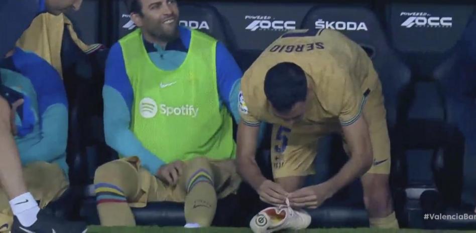 Busquets desata una bota de Piqué en el banquillo.