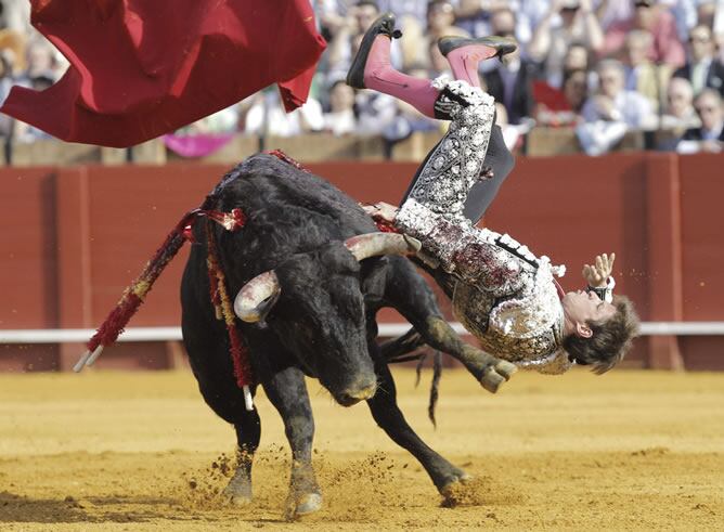 El diestro Julián López 'El Juli' es cogido por el primer toro de su lote durante la undécima corrida de abono de la Feria de Abril celebrada en la Real Maestranza de Sevilla, en la que ha compartido cartel con los matadores José María Manzanares y Antonio Nazaré