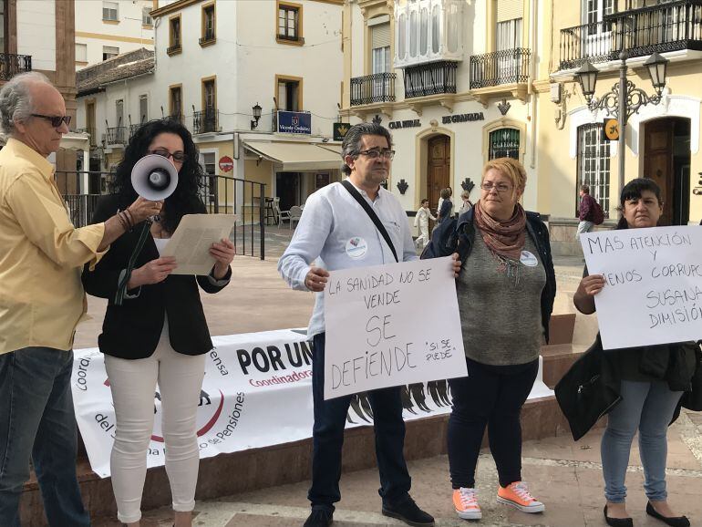 Varios protestantes muestran pancartas y leen un manifiesto en protesta de las listas de espera