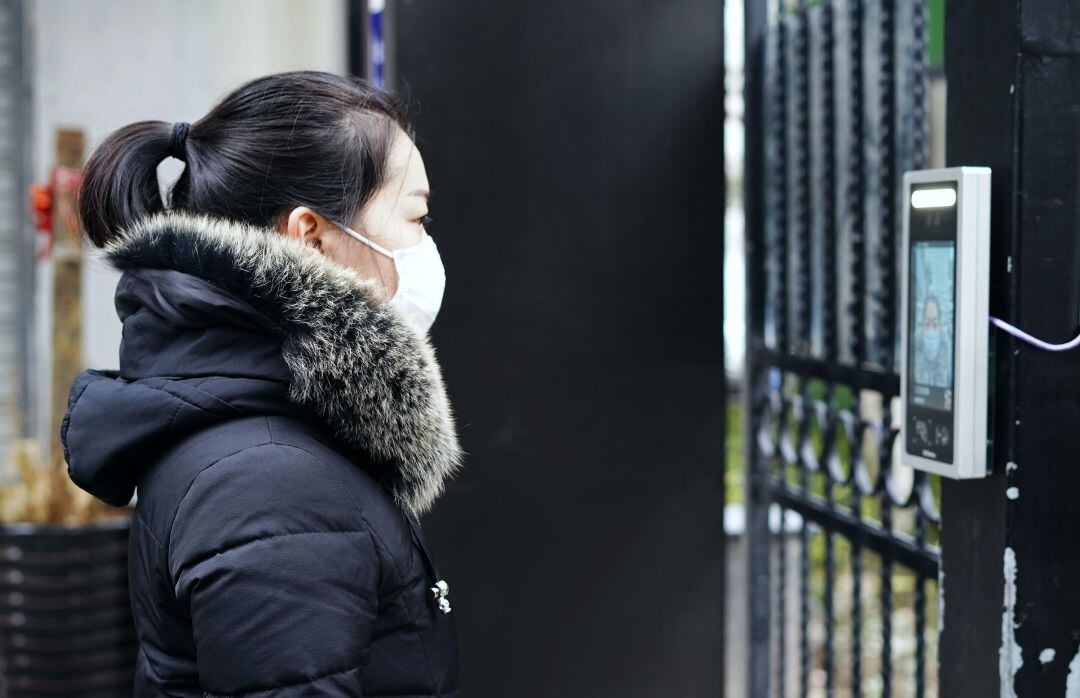 Una mujer con mascarilla usa un sistema de reconocimiento facial para acceder a una residencia en Hangzhou, China.