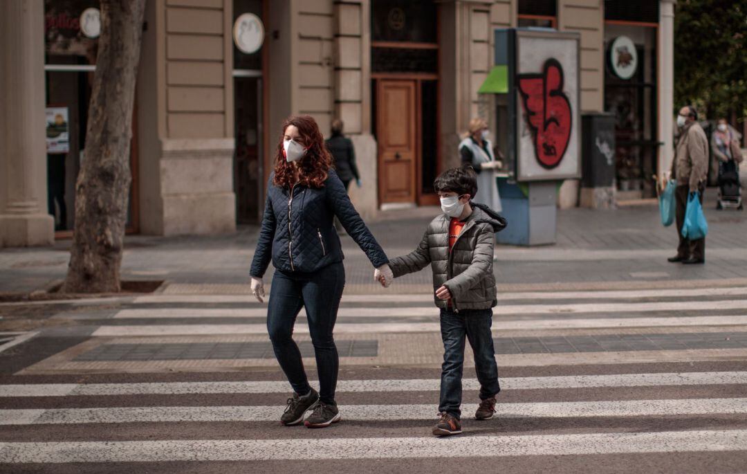 Una mujer acompañada de un niño cruza una calle en Valencia.