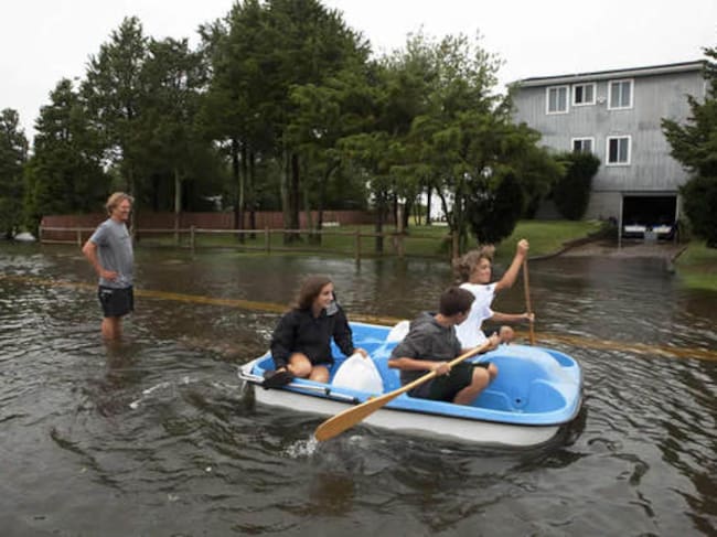 Unos vecinos del barrio de Southampton, en Nueva York, navegan por la calle inundada para llegar a sus casas