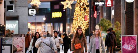 Personas transitando por una calle comercial en época de Navidad