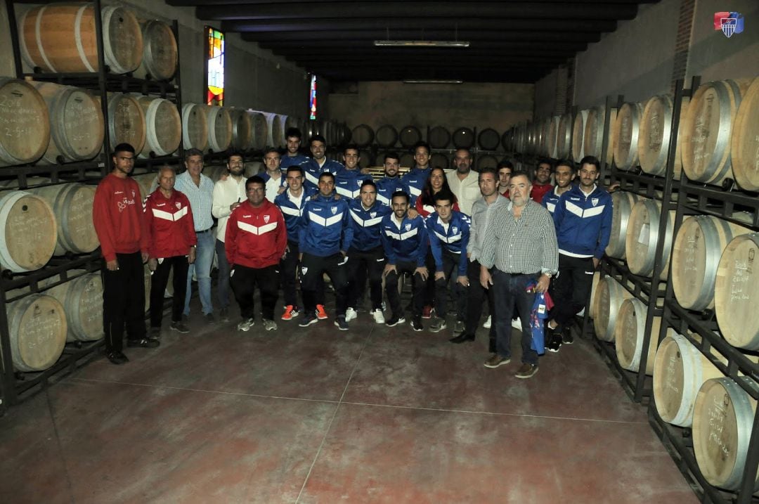 Jugadores,técnicos y directivos posan en el almacen donde reposan los vinos de Severino Sanz en las barricas