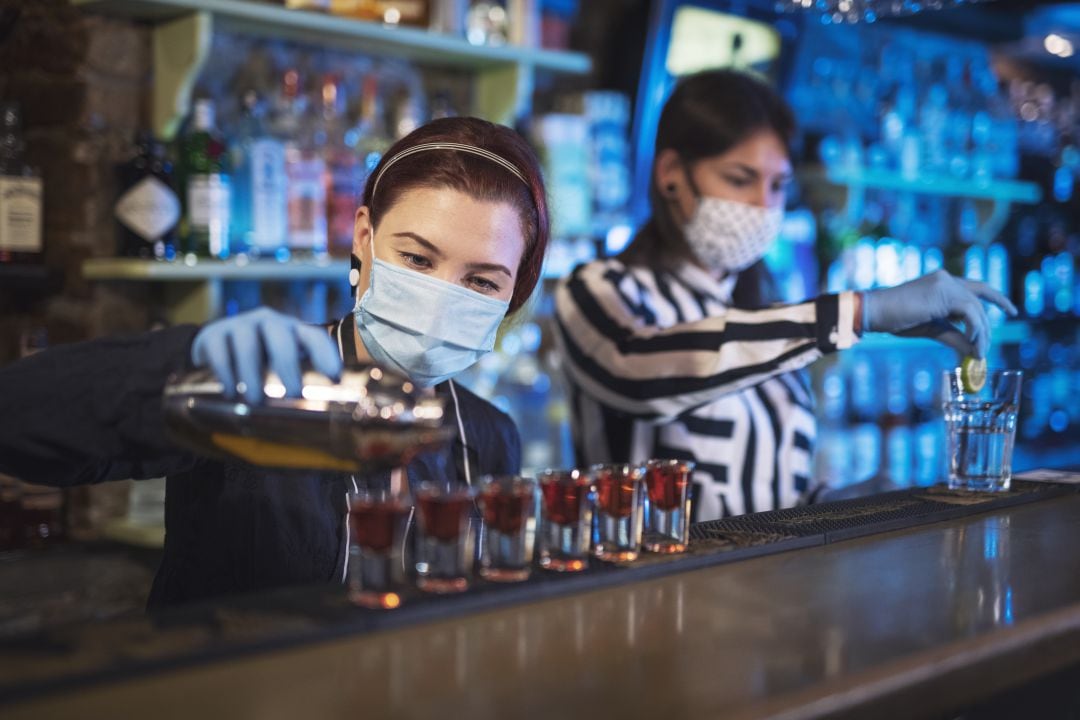 Dos camareras con mascarilla en el interior de un bar