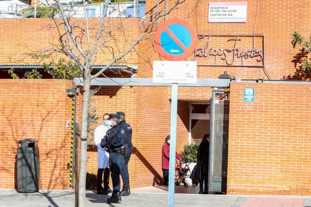 Un sanitario de la residencia habla con un agente de la Policía Nacional antes de recoger la caja con las dosis de la vacunas durante el primer día de vacunación contra la Covid-19 en España, en la residencia de mayores Vallecas, perteneciente a la Agencia Madrileña de Atención Social (AMAS)