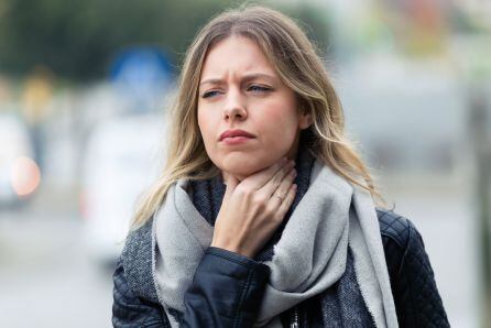 Una mujer se toca el cuello ante lo que podría ser un dolor de garganta