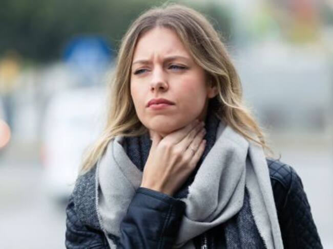 Una mujer se toca el cuello ante lo que podría ser un dolor de garganta