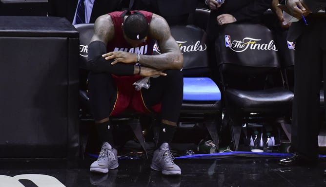 LeBron James trata de superar los calambres en el banquillo con una bolsa de hielo.