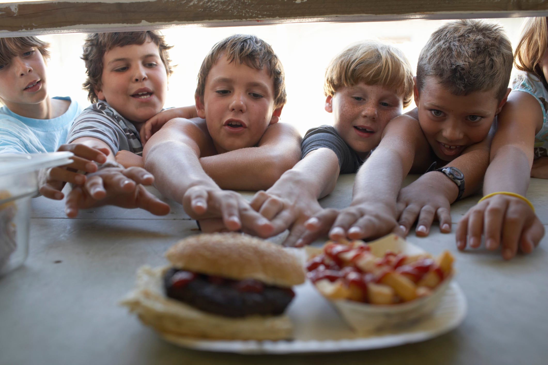 Unos niños intentan alcanzar una hamburguesa