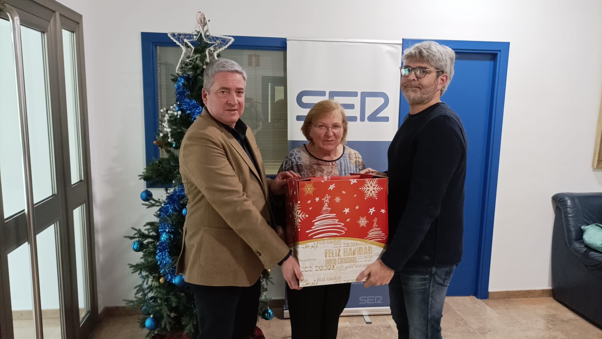 Cristina Burrial recibe la cesta de manos del director de Radio Huesca, Enrique Mored -izquierda-, y Agustín Cabrero, adjunto a la Gerencia de Supermercados Altoaragón / Francisco Aso