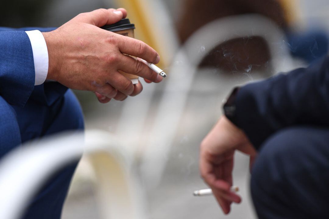 Dos hombres charlan mientras fuman un cigarro