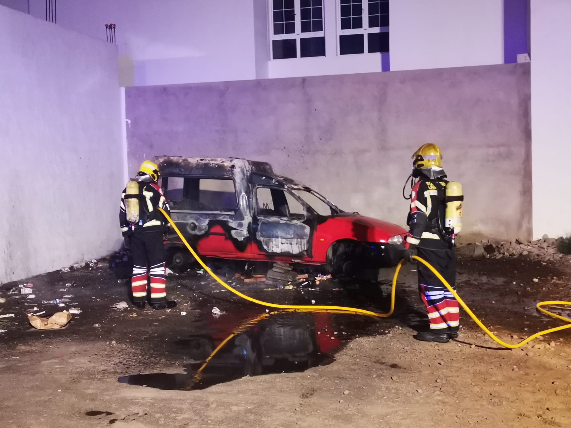 Bomberos de Lanzarote junto al vehículo incendiado.