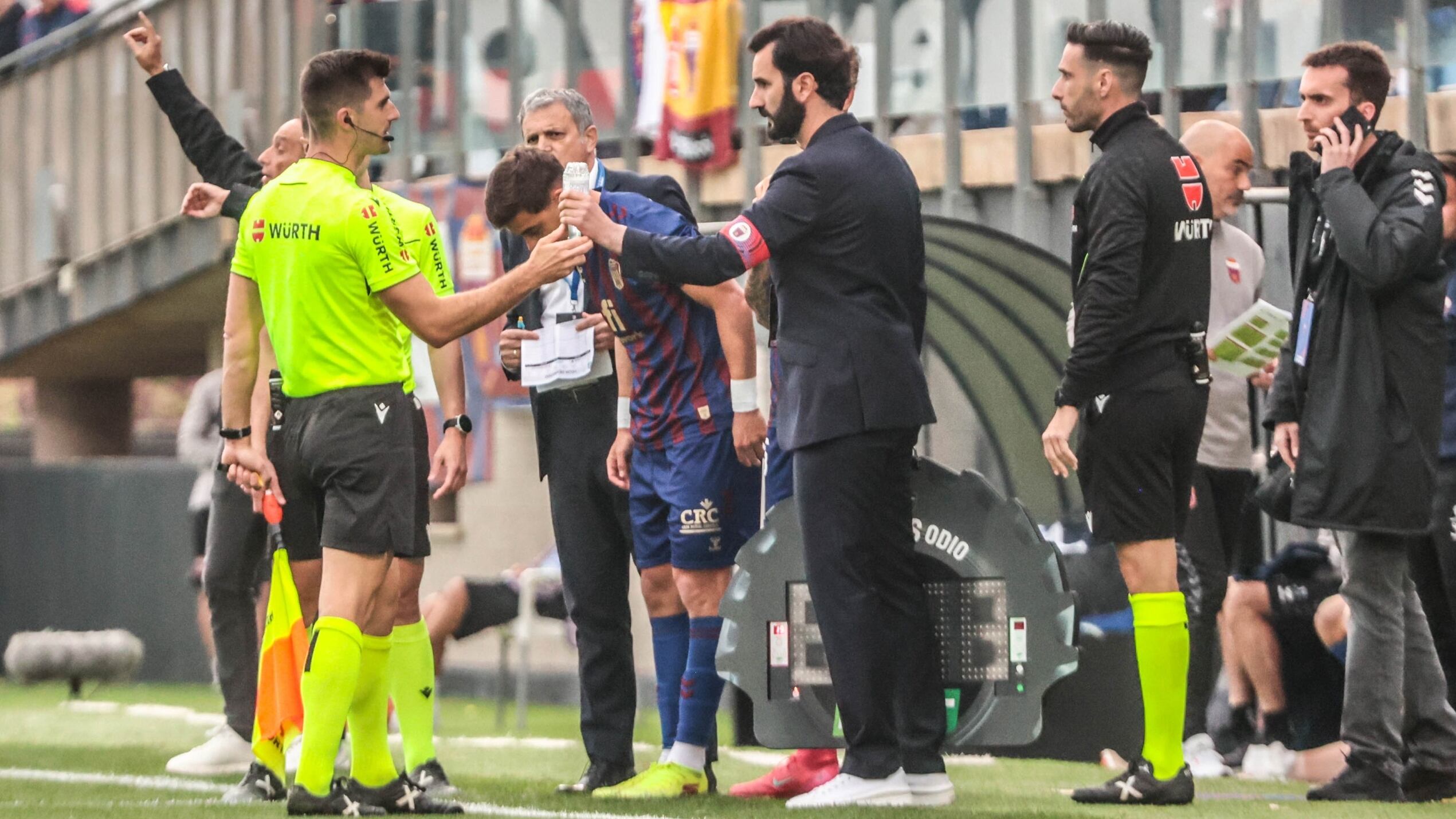 El árbitro entregando la botella al delegado de campo del Eldense