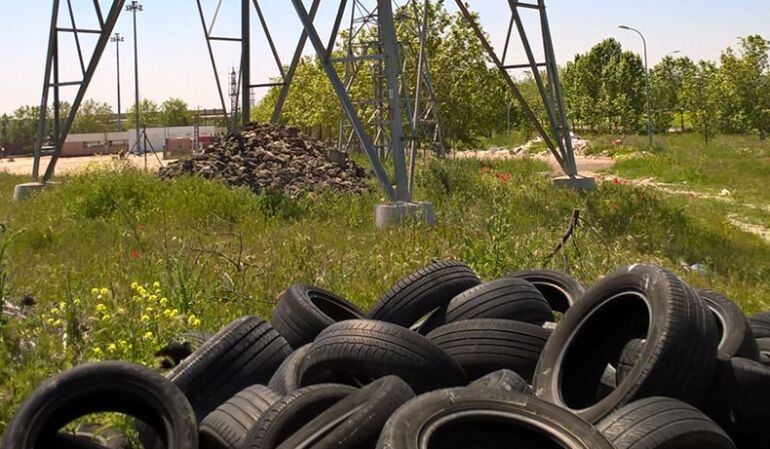 El vertido de neumáticos junto a una torre de alta tensión