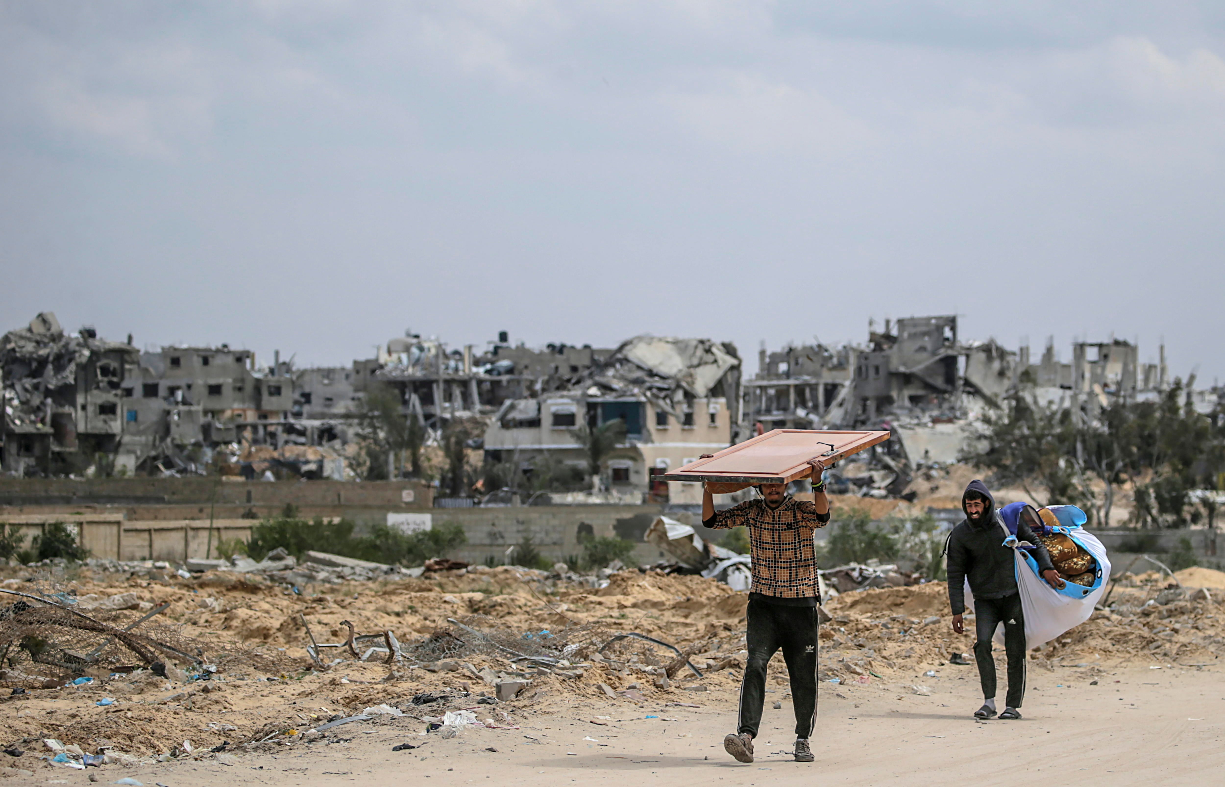 Palestinos llevando sus pertenencias huyendo de una zona atacada