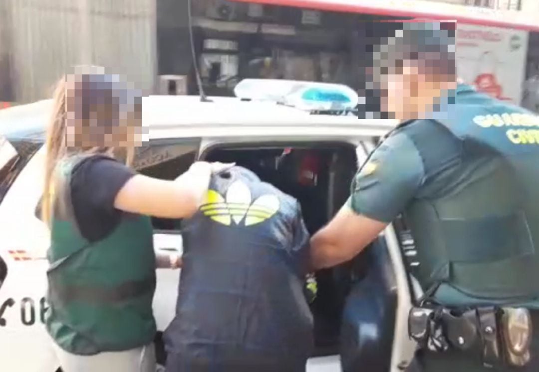 Agentes de la Guardia Civil introducen a uno de los detenidos en un coche patrulla 