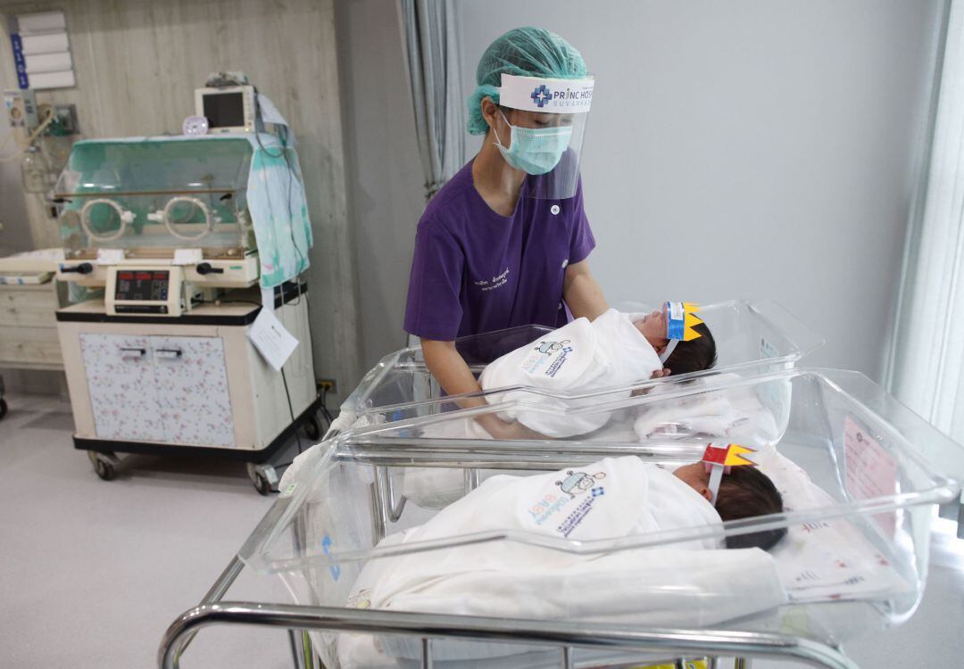 Una enfermera en Tailandia cuida a unos bebés con pantalla protectora