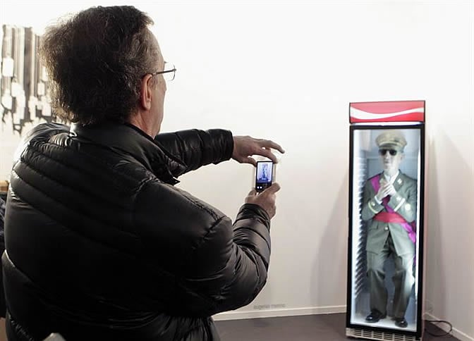 El vicepresidente de la Fundación Francisco Franco, Jaime Alonso, toma fotografías de la obra en la que aparece Franco vestido de militar dentro de una cámara frigorífica de bebidas,