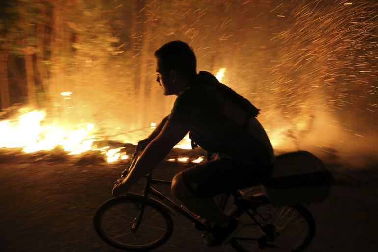 Un vecino intenta sofocar las llamas del incendio forestal de Arbo (Pontevedra), en el que se ha decretado la Situación 2 por la cercanía del fuego a núcleos de población. Las hectáreas de monte afectadas por los incendios forestales que se mantienen acti