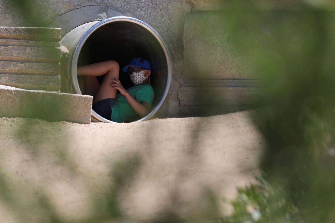 Un joven se protege del calor en el interior de una tubería en la zona de Madrid Río, durante una jornada de intenso calor registrado en la capital.