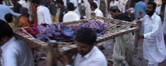 Ciudadanos llevan el cuerpo de una víctima tras el doble atentado suicida en una mezquita de Pakistán