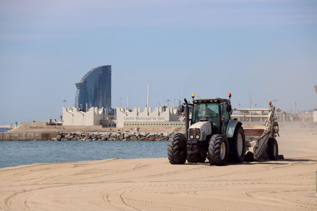 Un tractor haciendo labores de limpieza en la playa del Bogatell de Barcelona