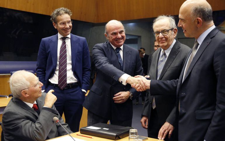  El ministro español de Economía, Luis de Guindos (c), estrecha la mano del comisario europeo de Asuntos Económicos y Financieros, Pierre Moscovici (d), en presencia del ministro de Finanzas alemán, Wolfgang Schäuble (i), el presidente del Eurogrupo, Jero