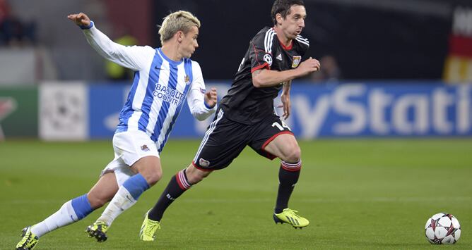 El jugador del Bayer Leverkusen Roberto Hilbert es perseguido por el delantero francés Antoine Griezmann de la Real Sociedad durante el partido del grupo A de la Liga de Campeones disputado en el BayArena de Leverkusen