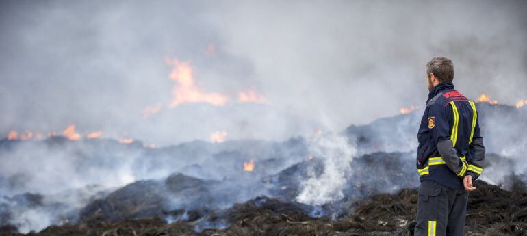 Un bombero observa los neumáticos que arden en el incendio de Seseña (Toledo), y cuyas labores de extinción continúan