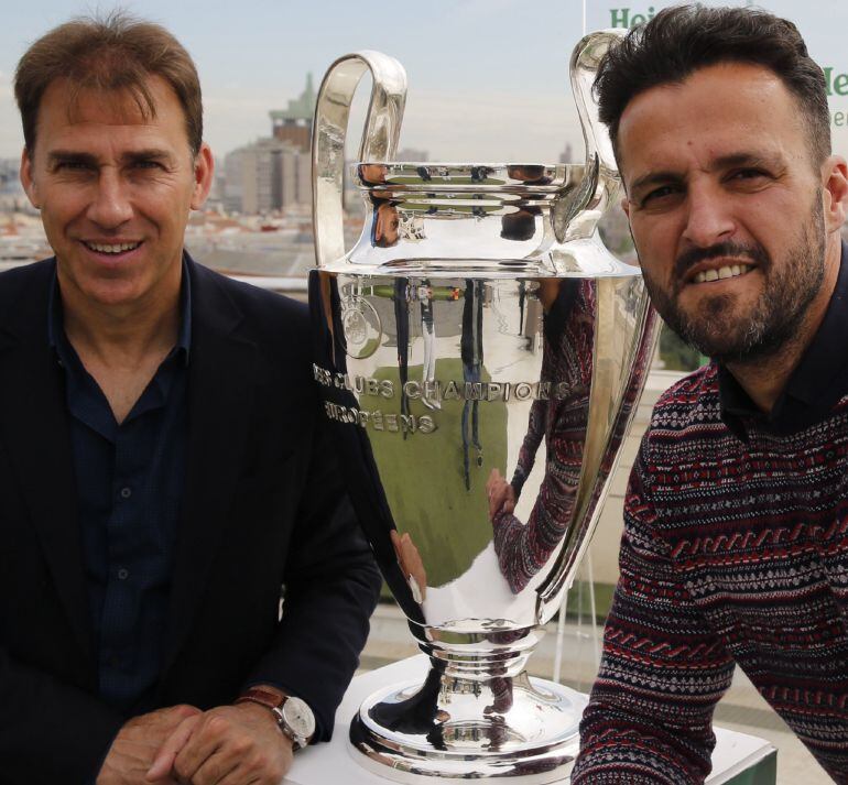 Los exjugadores del Atlético de Madrid y del Real Madrid, Rafael Martín Vázquez y Kiko Narváez, respectivamente, posan hoy en el Palacio de Bellas Artes junto a una de las dos réplicas de la de la Copa de Champions que hoy se han colocado en Madrid