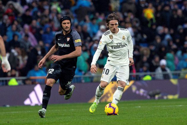 El centrocampista croata del Real Madrid, Luka Modric (d), lucha por el balón ante el centrocampista argentino del Sevilla FC, Franco Vázquez (i), durante el partido correspondiente a la 20ª jornada de LaLiga Santander que disputan hoy en el estadio Santiago Bernabéu, en Madrid.