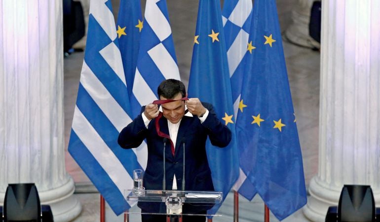 El primer ministro griego, Alexis Tsipras, ofrece una rueda de prensa mientras se pone una corbata, en Atenas.