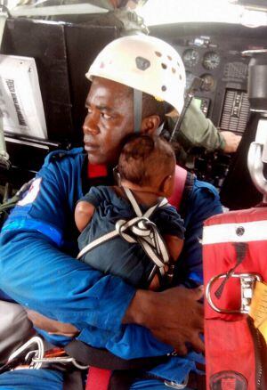 Un miembro del equipo de salvamento abraza al hijo de la señora María Nelly.