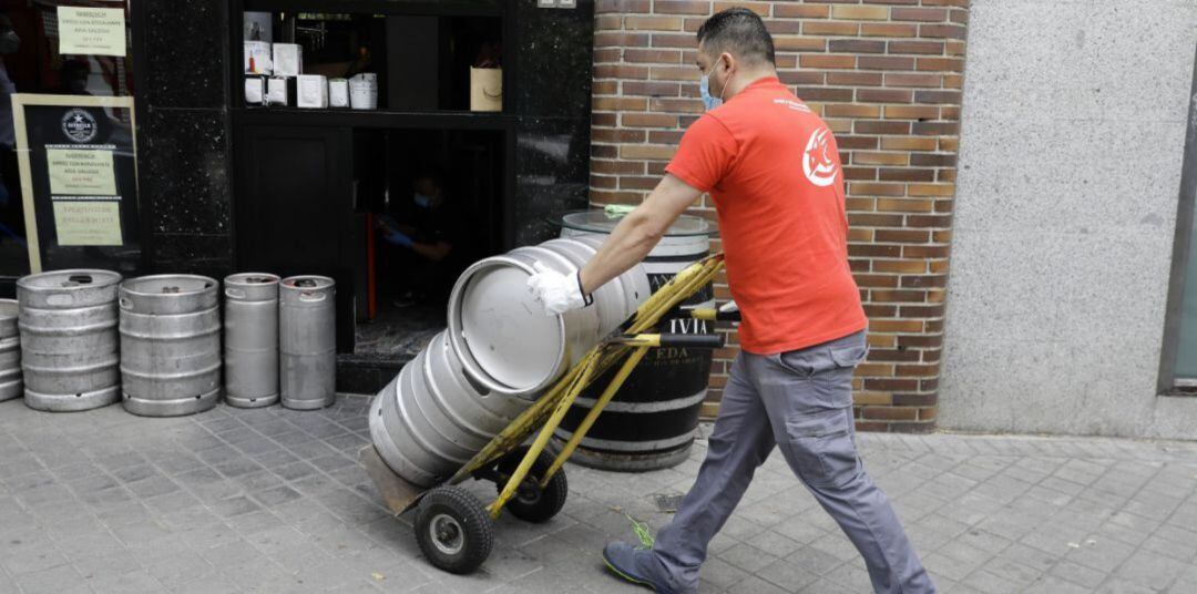 Un repartidor acercando barriles de cerveza a un establecimiento